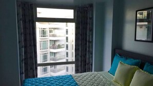 Une chambre d’hôtel avec un lit, des rideaux et une fenêtre donnant sur un immeuble.