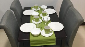 Une table de salle à manger rectangulaire, agrémentée d’un chemin de table vert, entourée de quatre chaises grises à revêtement.