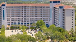 A multi-story hotel with a central courtyard, surrounded by lush greenery and a parking lot. - Rate Reduced! Tops'l Condo -  Walk to Beach, Tropical Pool, Balcony. (Miramar Beach)
