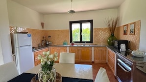Una cocina amplia con armarios de madera, un refrigerador y un comedor con una mesa lista para dos.