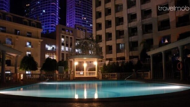 A nighttime pool area with a gazebo, surrounded by high-rise buildings. - Eastwood City Secured w/ Panoramic View (Quezon City)
