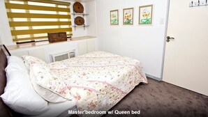 A master bedroom with a queen bed, a window with blinds, a radiator, and a door with a handle. - Eastwood City Secured w/ Panoramic View (Quezon City)