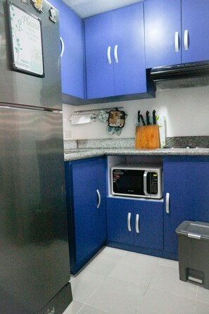 Compact kitchen area with a refrigerator, microwave, and sink, offering basic amenities for a convenient stay.