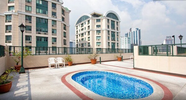 A jacuzzi pool on the 26th floor with potted plants and chairs around it.