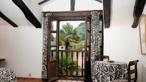 Una habitación con una mesa de comedor y sillas, una ventana con cortinas, y vista a zonas verdes al exterior.