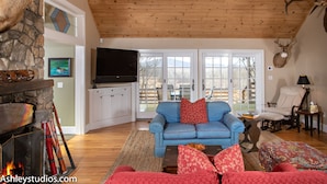 A cozy living room with a stone fireplace, a blue sofa, and a mounted deer head.