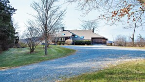 A two-story house with a gravel driveway leading to a garage.