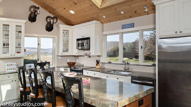 A modern kitchen with white cabinets, a large island, and a skylight.