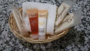 A wicker basket containing four Eligianti body care products on a granite countertop. - Valli Hi Motel (San Ysidro)