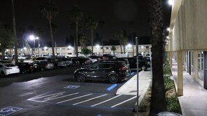 A nighttime parking lot with multiple cars, a handicapped parking space, and a building with a modern facade. - Valli Hi Motel (San Ysidro)