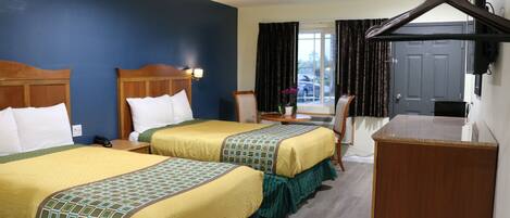 A hotel room with two beds, a desk, a chair, and a wardrobe.