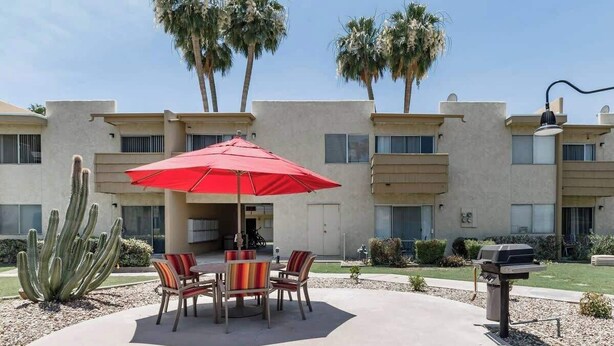 A patio with a red umbrella, outdoor seating, a cactus, and a barbecue grill. - Walk to Old Town | 2 King Beds + 4 Heated Pools (Scottsdale)