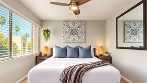 A bedroom with a bed, bedside lamps, a ceiling fan, and artwork on the walls. - Walk to Old Town | 2 King Beds + 4 Heated Pools (Scottsdale)
