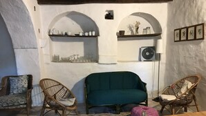Una sala acogedora con un sofá verde, sillas de mimbre, una mesa de madera y un tapete a rayas.
