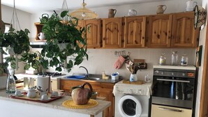 Una cocina con armarios de madera, lavadora, estufa y diversos utensilios de cocina.