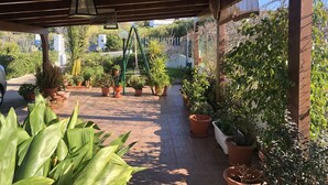 Un porche cubierto con plantas en macetas y un columpio.