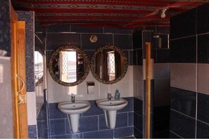 A bathroom with two sinks, mirrors, and a shower area.