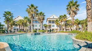 Una piscina rodeada de palmeras y edificios de varios pisos con balcones.