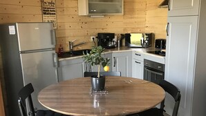 A wooden-paneled kitchen with a round table and chairs, a refrigerator, a coffee maker, and a potted plant. - Atypical gîte for 4 people 15 min from Angers (Saint-Martin-du-Fouilloux)