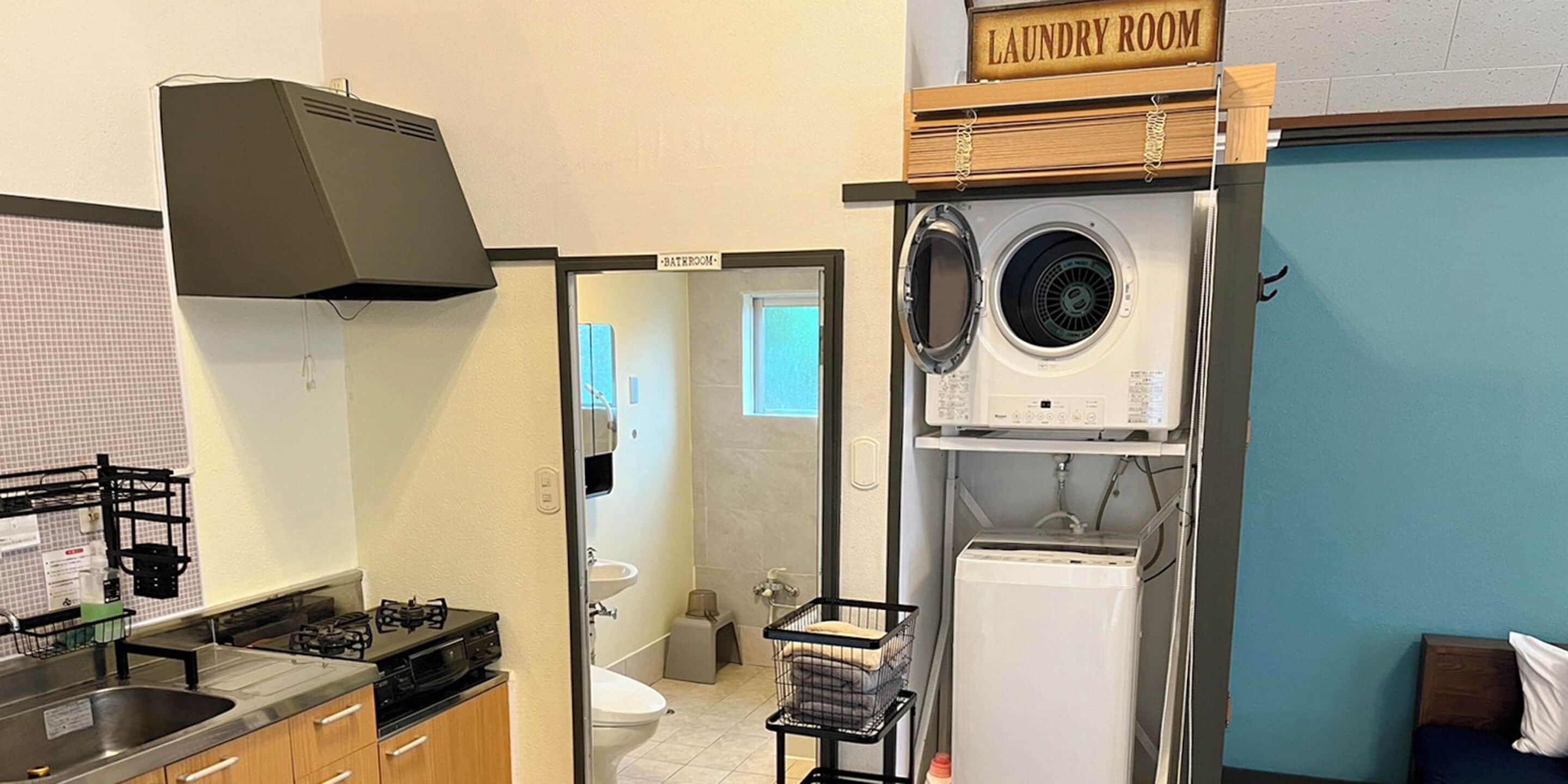 Cocina compacta con estufa a gas, pileta y cartel de cuarto de lavado.