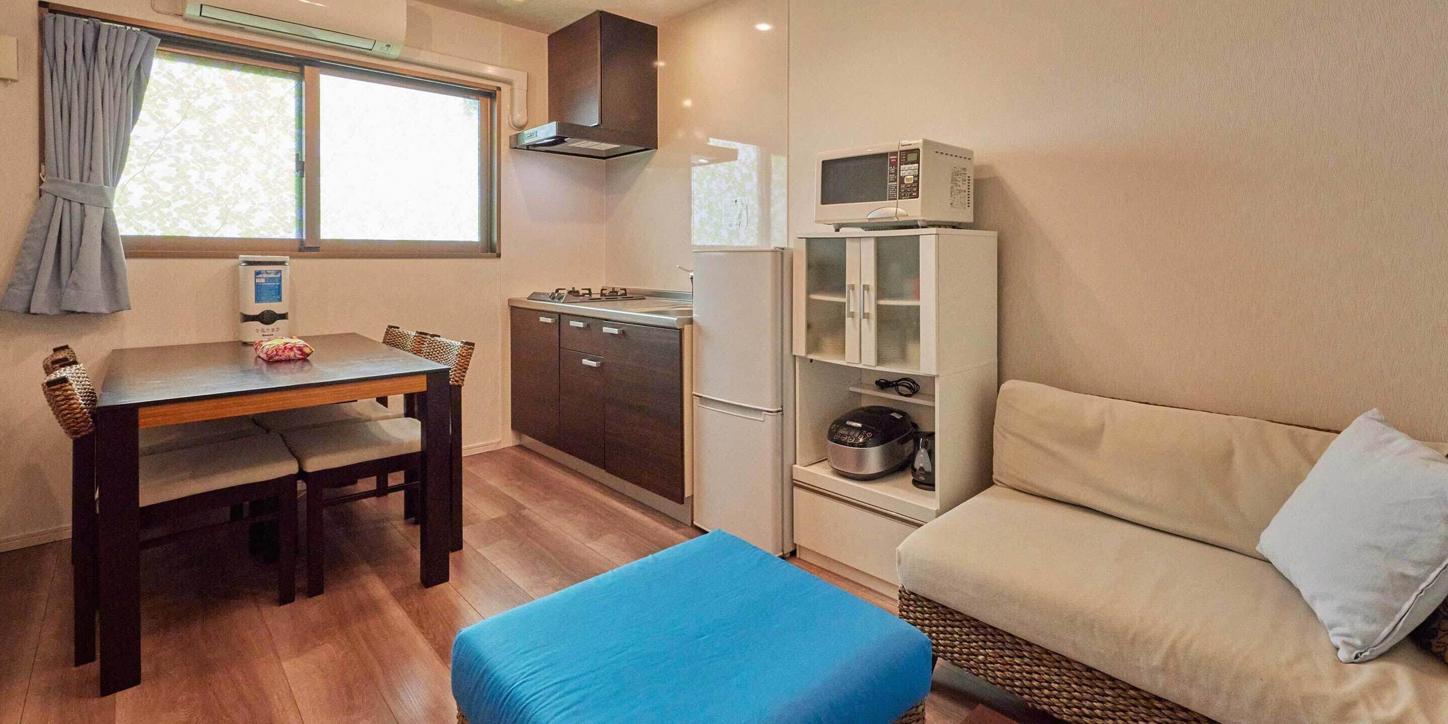 Une cuisine compacte comprenant une table à manger, un canapé et un four à micro-ondes posé sur un meuble.