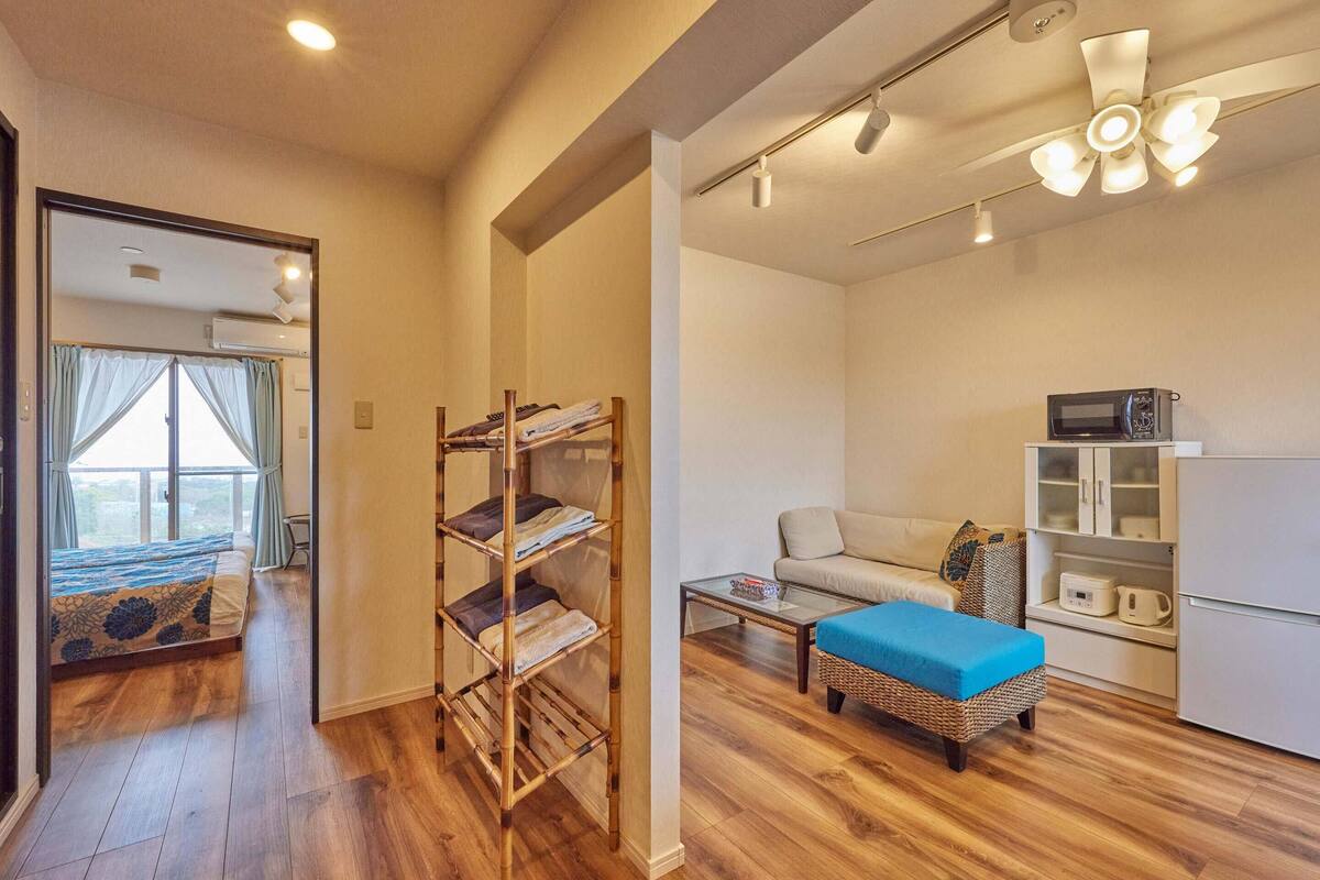 A compact living space with a bunk bed, a sofa, a coffee table, and a microwave on a cabinet.