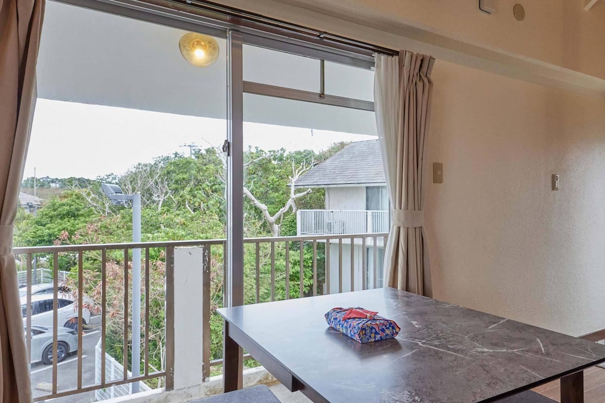 A balcony with a table, a view of the street, and a door with a frosted glass panel.