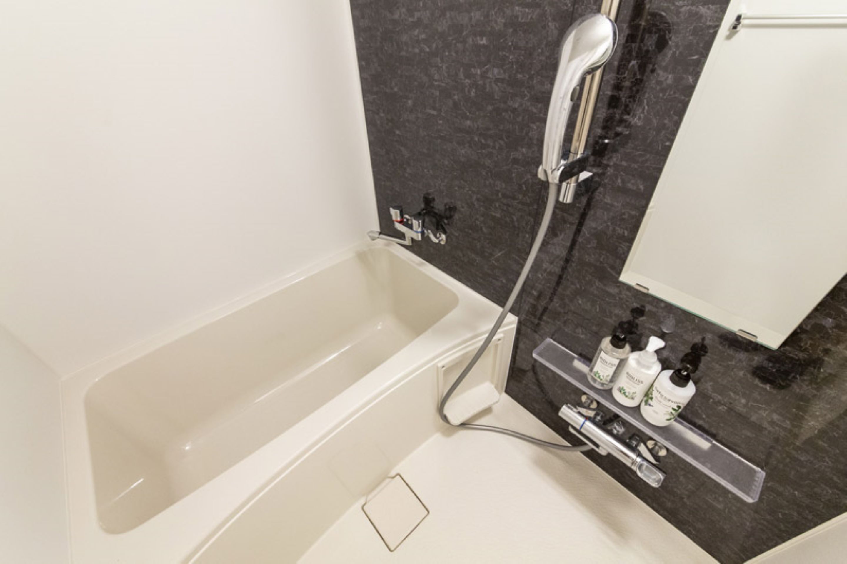 Ein modernes Badezimmer mit einer Badewanne, einer Dusche und einem Waschbecken mit Pflegeprodukten.