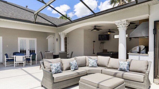 Un patio techado al aire libre con sofá modular, mesa de comedor y sillas.