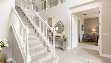 A staircase with white railings leading to a second floor. A mirrored console table is visible in the background.