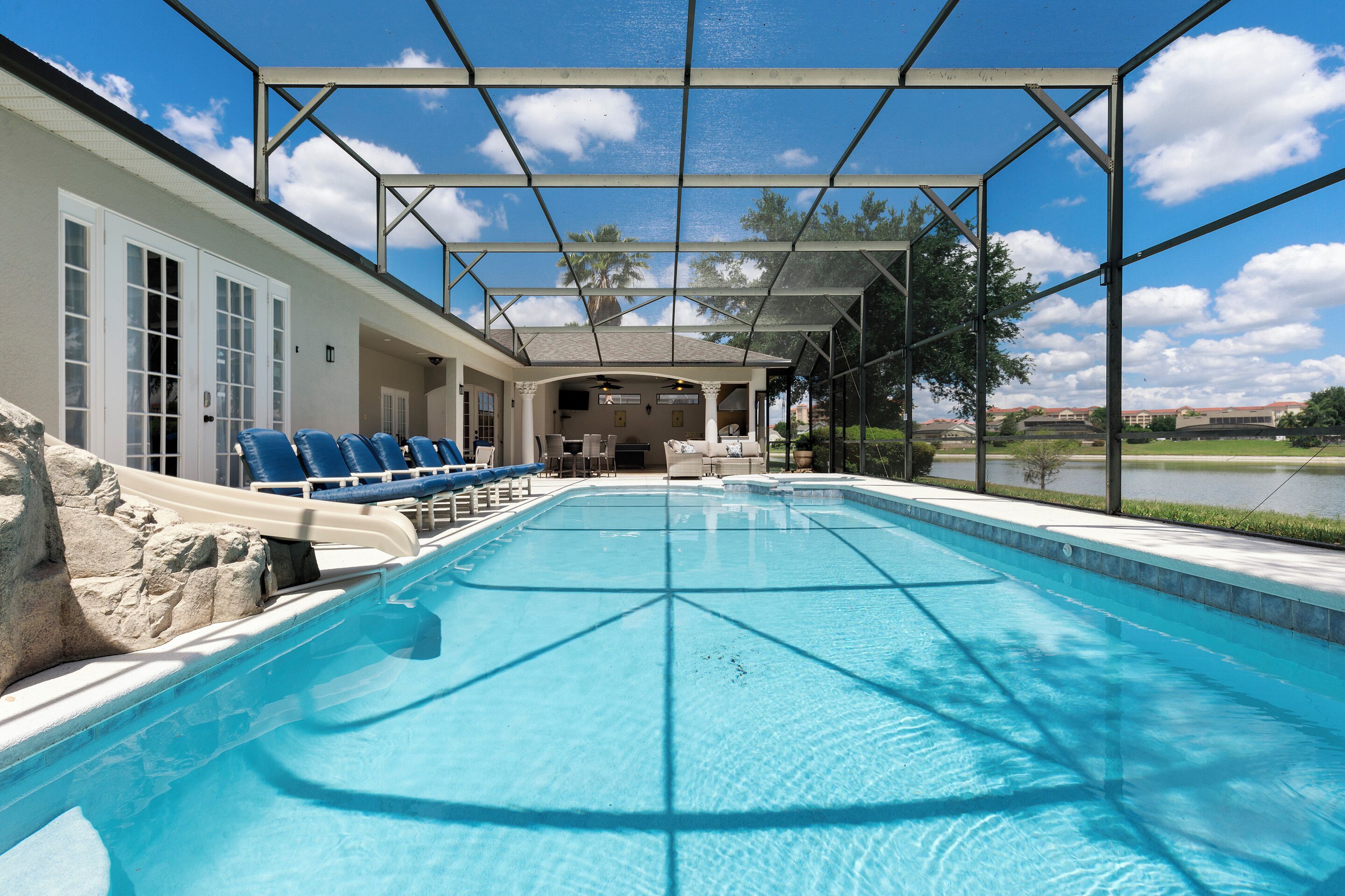 A swimming pool with lounge chairs and a covered area.