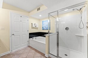 Une salle de bain avec une baignoire, une douche à parois de verre et une porte blanche.