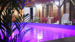 Ein Außenpoolbereich mit Holzterrasse, umgeben von Stühlen und Tischen, mit einem Holzzaun im Hintergrund.