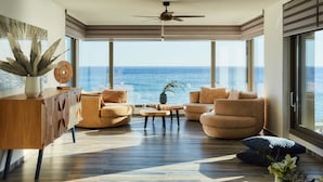 A modern living room with a large window overlooking the ocean, a ceiling fan, and a wooden console table. - Beachfront Moonlight villa for large groups (Koutsouras)
