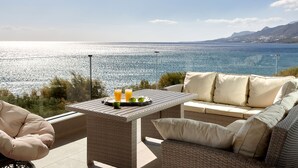A balcony with wicker furniture, a table with a tray of fruit and drinks, and a scenic view of the sea and mountains. - Beachfront Moonlight villa for large groups (Koutsouras)