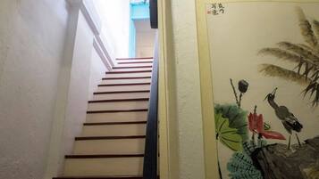 A staircase leading to a room with a wall-mounted painting of birds and foliage.
