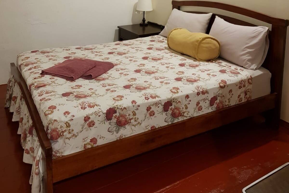 A neatly made bed with floral bedding, a bedside lamp, and a framed picture on the wall.
