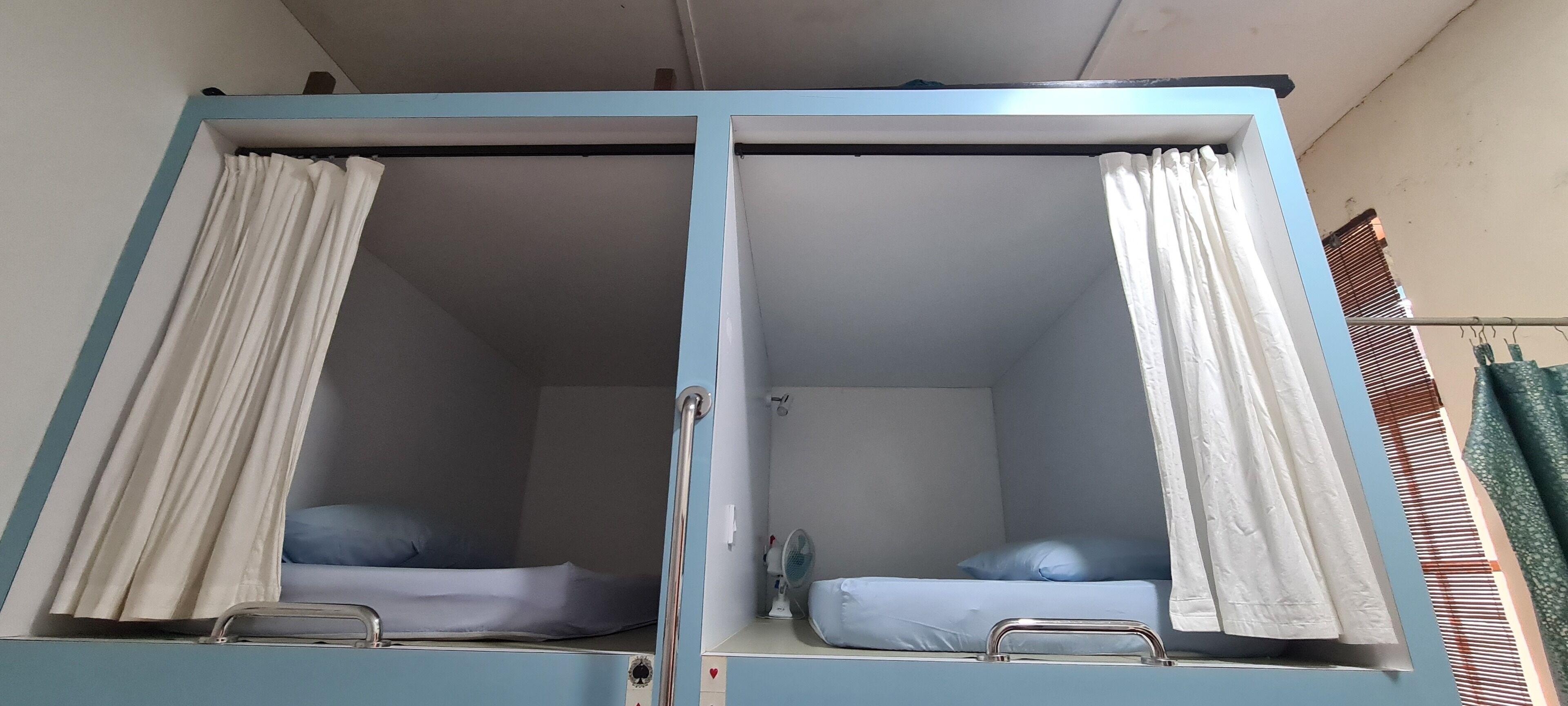 A room with two beds, each with a pillow and a metal frame.