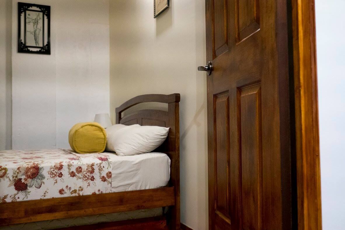 A bedroom with a wooden bed, a yellow pillow, and a white pillow.