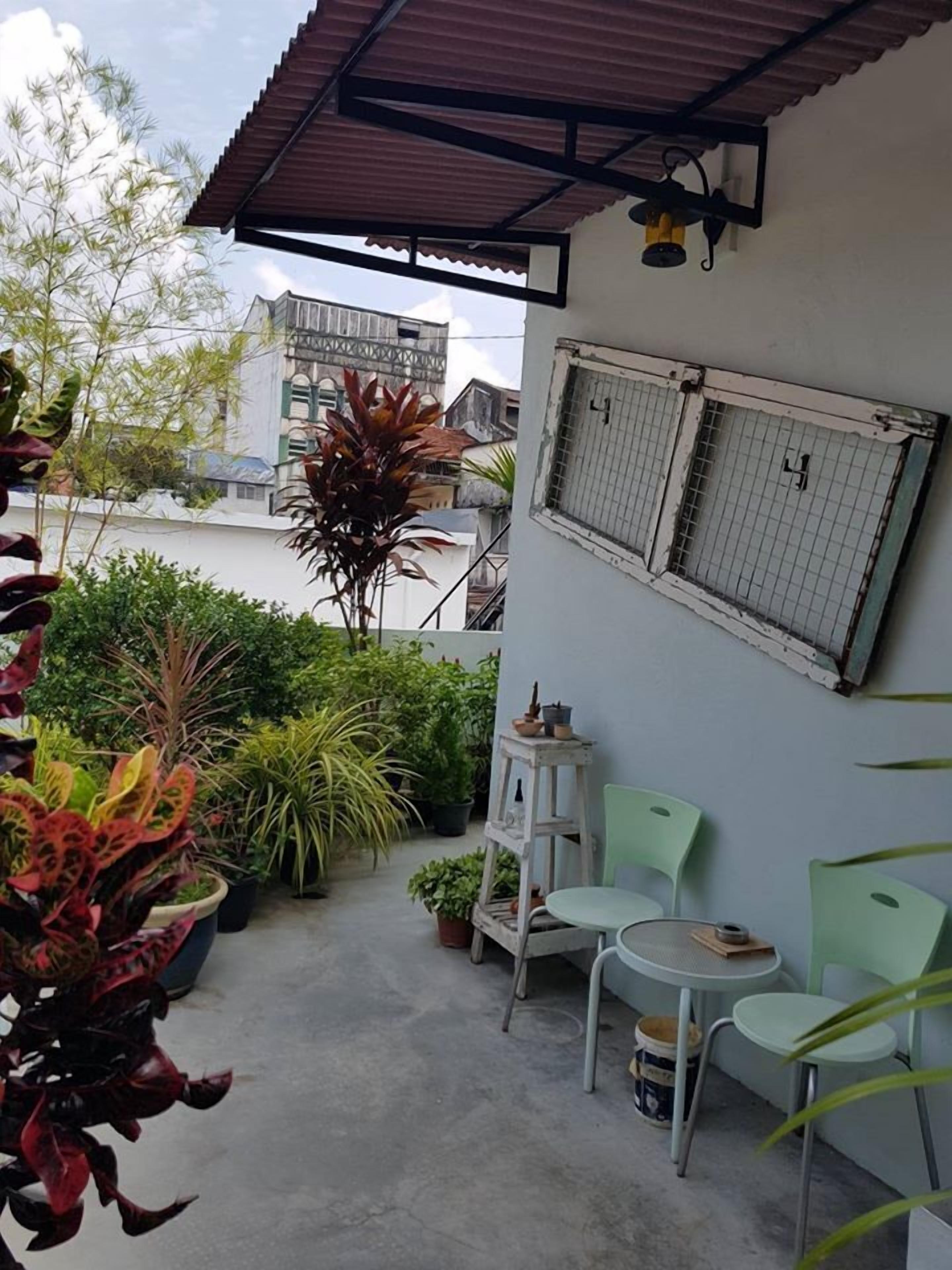 A balcony with potted plants, a small table, and two chairs.