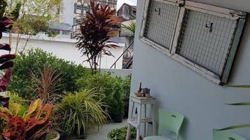 A balcony with potted plants, a small table, and two chairs.