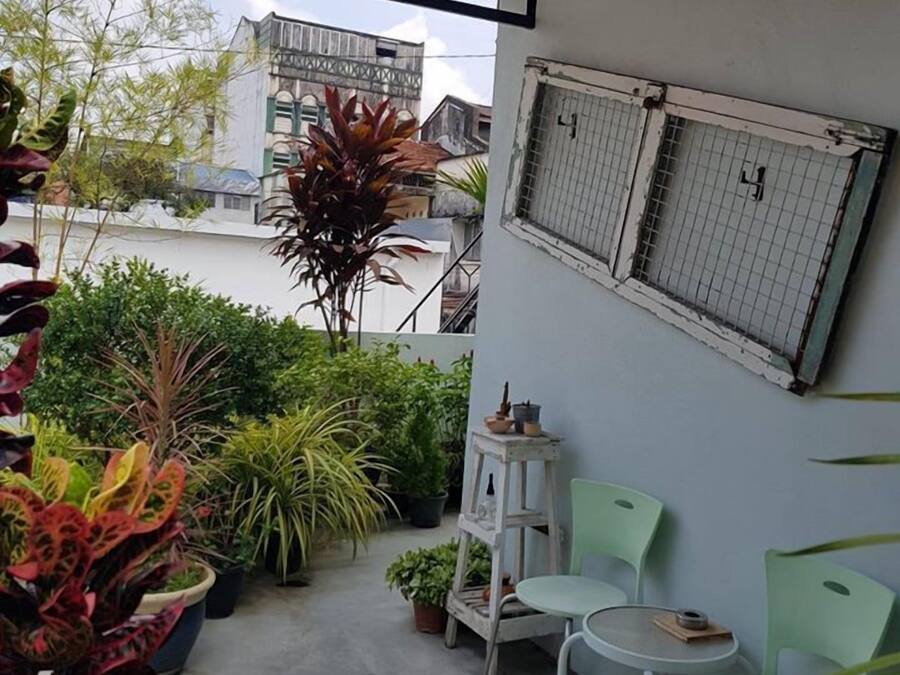 A balcony with potted plants, a small table, and two chairs.