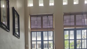 Una habitación con dos sillas de madera, una mesa pequeña con una lámpara y una ventana con persianas.