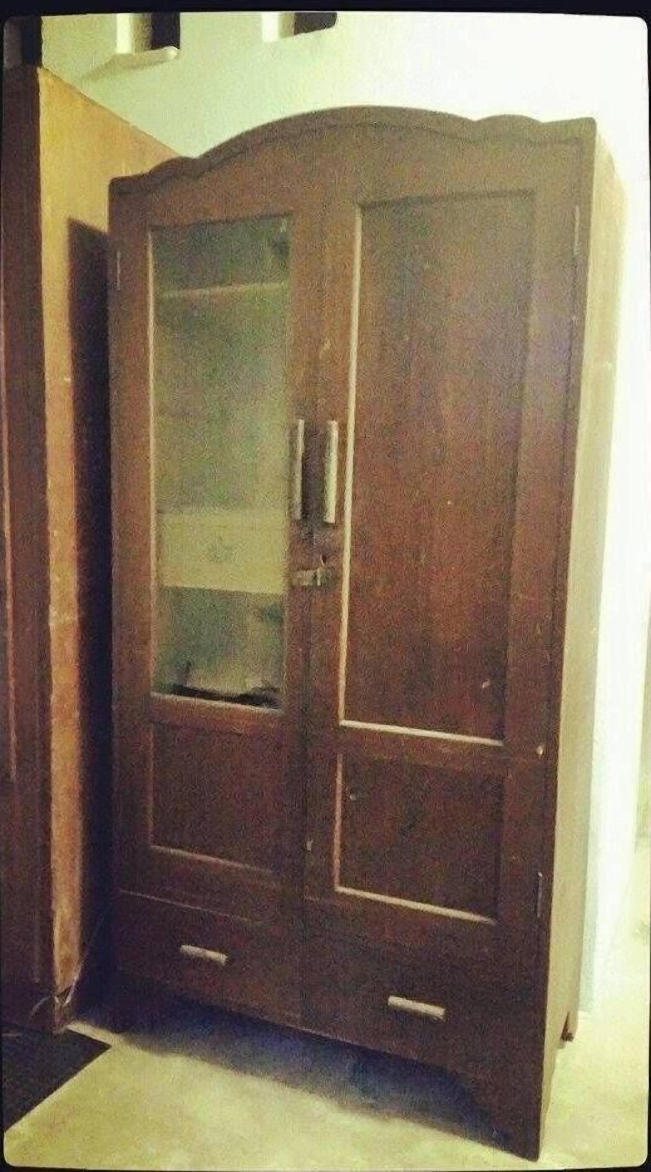 A wooden wardrobe with two doors and a mirrored section.
