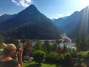 A mountainous landscape with a river and a person using binoculars.
