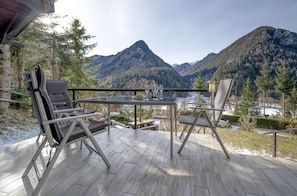 Relax on the terrace with a glass-top table and lounge chairs, taking in the breathtaking views of the surrounding mountains and serene body of water.