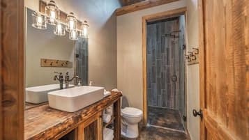 A bathroom with two sinks, a toilet, and a shower area.