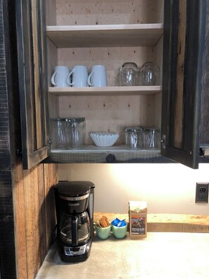 Kitchen area with a cabinet for storage and a coffee maker.