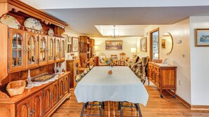 Une salle à manger avec une longue table, des meubles en bois et divers objets décoratifs.