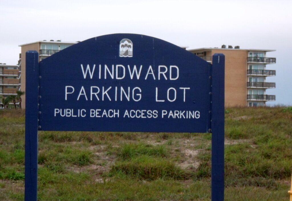 A sign for Windward Parking Lot with a public beach access label.